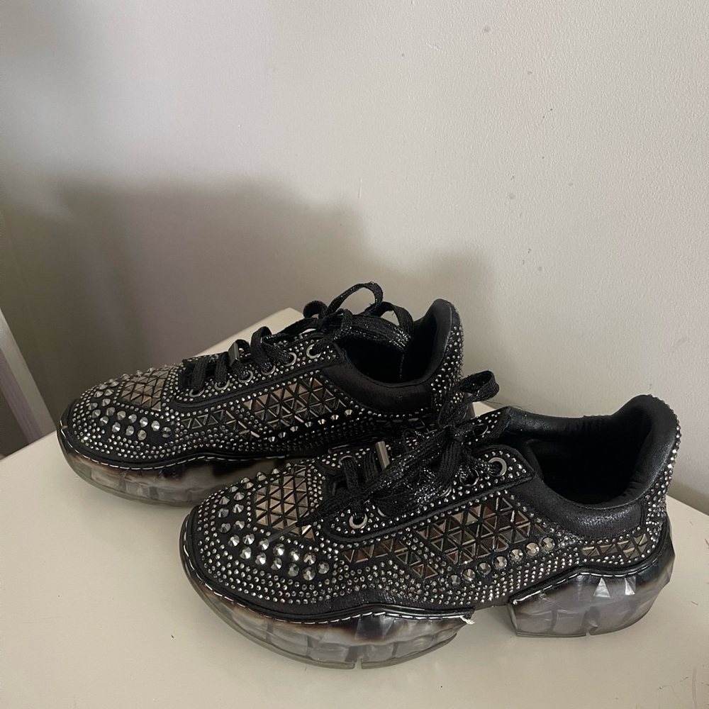 La Sheelah studded, sparkly black sneakers with clear/black sole.